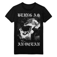 image of a black tee shirt on a white background. tee has a full body print in white that says being as at the top with two wolves with their mouth open in a fight below and an ocean across the bottom
