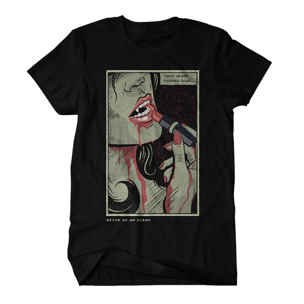 image of a black tee shirt on a white background. tee has a full chest print of a comic book character. a vampire woman putting on lipstick is shown from below the eyes down with the words your heart turned cold at the top right and being as an ocean at the bottom left.