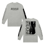 image of the front and back of an ash colored long sleeve tee shirt on a white background. front of the long sleeve is on the left and has a center chest print that says being as an ocean. two sleeve prints on each sleeve. back of the long sleeve is on the right and has a full back print in black that says being as an ocean