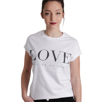 image of a white woman with her hair up and hand in pocket wearing a white tee shirt on a white background.  tee has a full chest print in black that says LOVE, being as an ocean