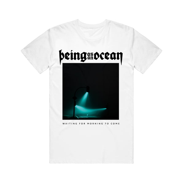 image of a white tee shirt on a white background. tee has a full body print. on top in black says being as an ocean. below is an image of three traffic and street lights illuminating in green. waiting for the morning to come is written across the bottom of the image in black.