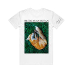 image of a white tee shirt on a white background. tee has full body print that says in black on top, being as an ocean with a photo of a sleeping fox on green grass.  small print in black on the right sleeve that says dear god 10 years