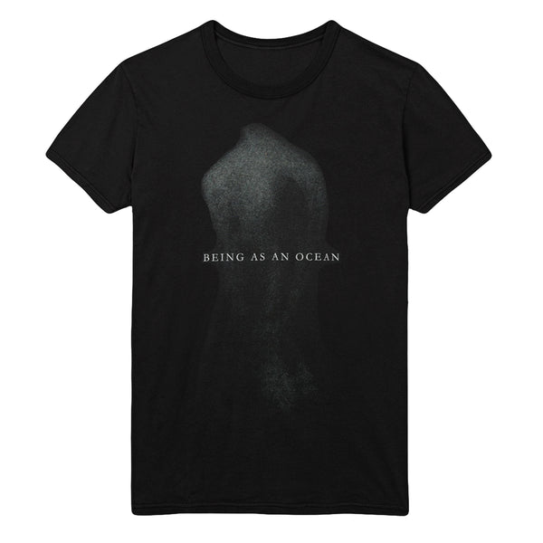 image of a black tee shirt on a white background. tee has a full body print in speckled grey of a persons nude back with the words being as an ocean written over the center in white.